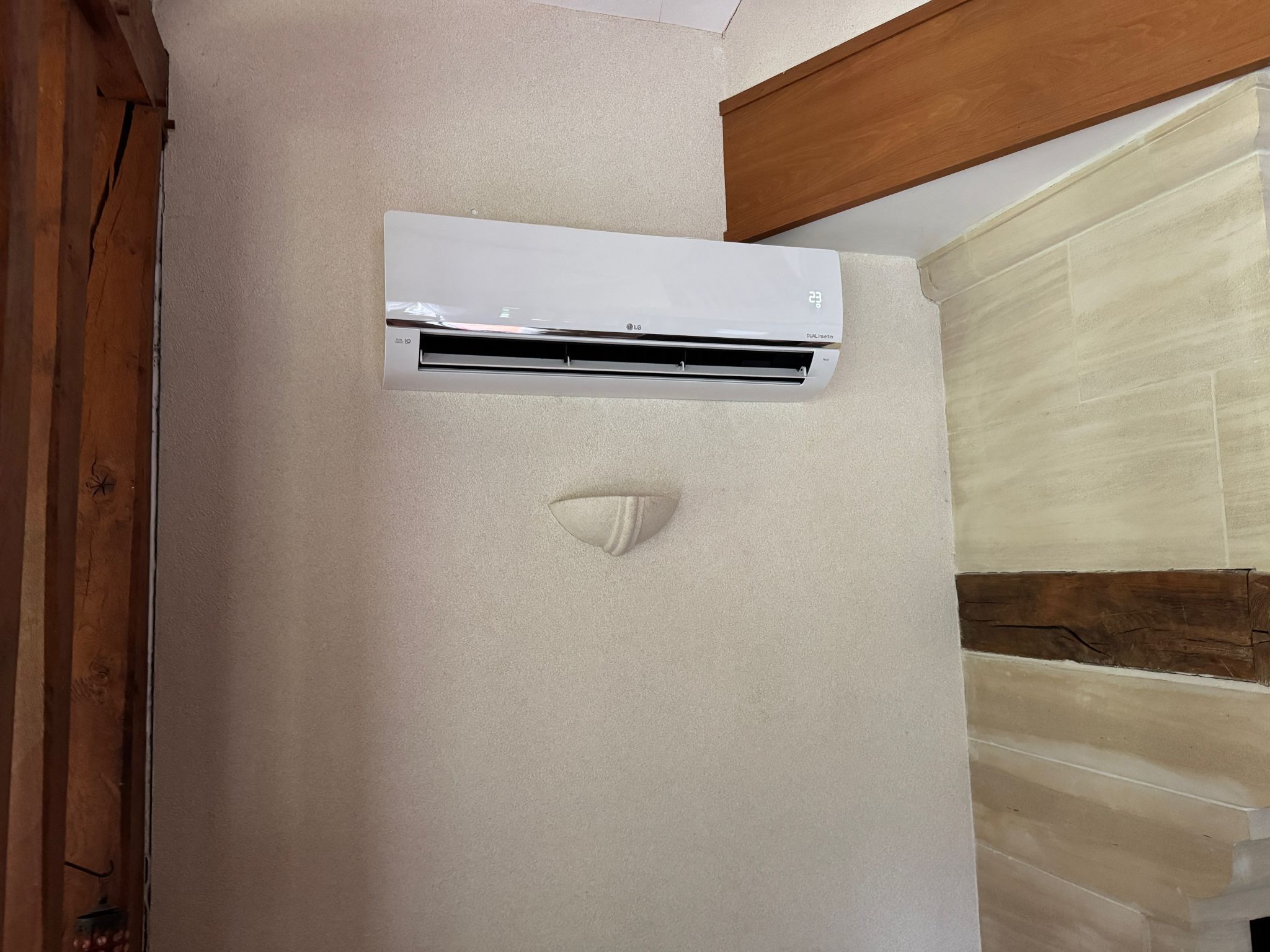 Unité intérieure de climatisation réversible LG Dual Inverter installée par AUDRIEU dans une pièce en pierre, Honfleur