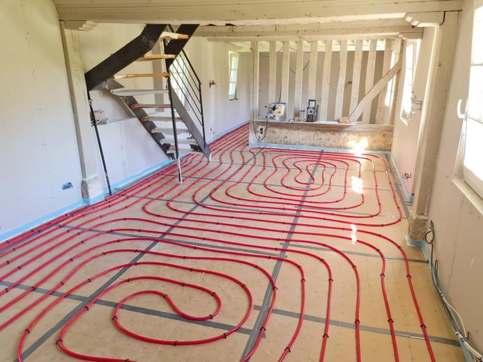 Plancher chauffant en cours de pose dans une maison à colombages